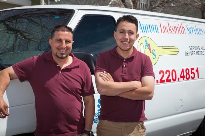 Two Aurora Locksmith Services technicians standing in front of their company van