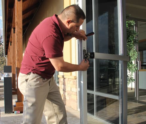 A technician working on the lock of a glass storefront door
